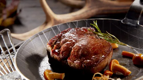 Cooked steak in a pan with mushrooms.