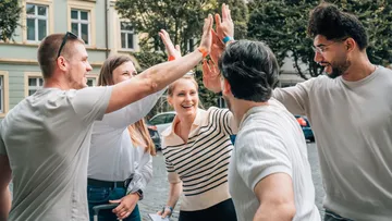 Group high-fiving outdoors on street.