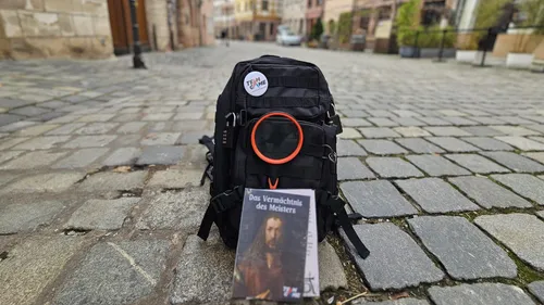 Backpack and book on cobblestone street.