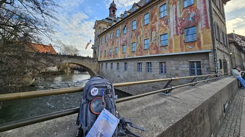 Backpack on a river bridge near ornate building.