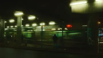 Verschwommener Zug, der nachts an Menschen vorbeifährt.