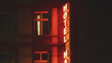 Neonschild mit der Aufschrift „Hotel“ am Gebäude bei Nacht.