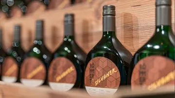 Weinflaschen mit der Aufschrift „Silvaner“ auf einem Holzregal.