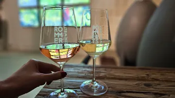 Two wine glasses on wooden table, colorful background.