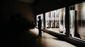 Silhouette people near metal tanks in dark room.