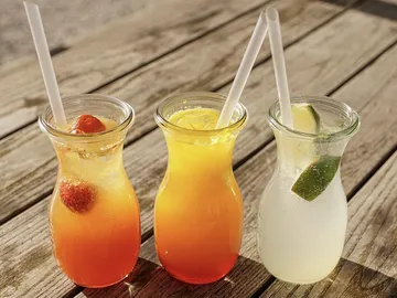 There are three drinks in glasses on a wooden table.