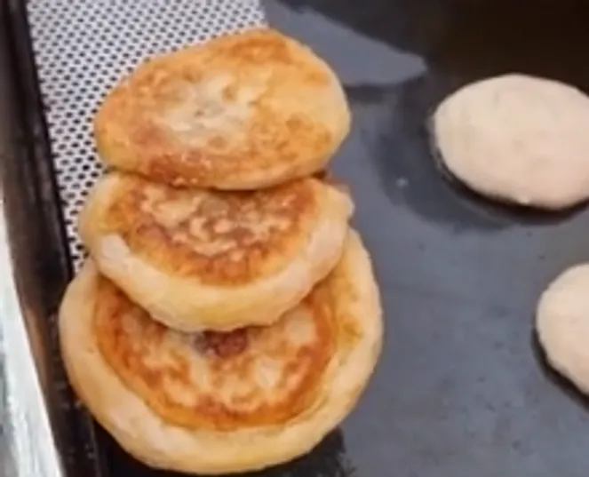 Three fried dumplings stacked on a griddle.