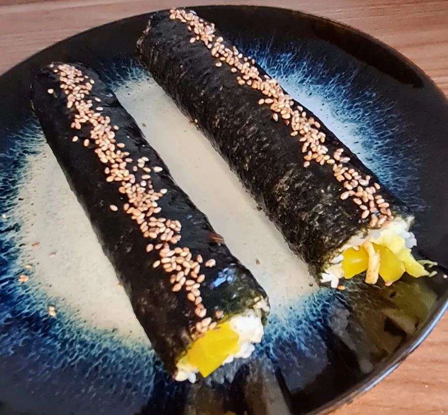 Two seaweed rolls with sesame seeds on a plate.
