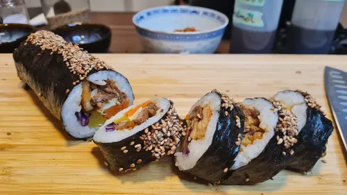 Kimbap rolls with sesame seeds on table.