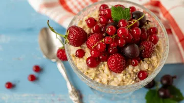 Haferflocken garniert mit roten Beeren, Löffel daneben.