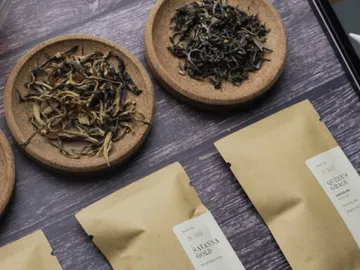 Dried tea leaves arranged in trays and paper bags.