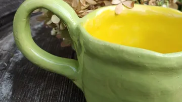 Green ceramic mug on wooden surface.