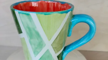 Bunter Becher mit geometrischen Mustern, Holzhintergrund.
