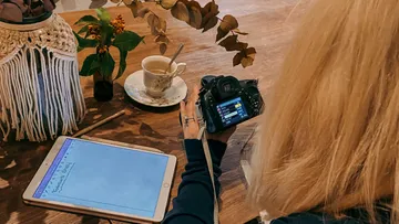 Person, die Kaffee und Tablet auf dem Tisch fotografiert.