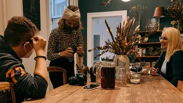 Drei Personen sitzen an einem Tisch und unterhalten sich drinnen.