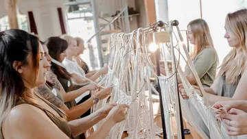 Women make artistic rope arrangements together in bright surroundings.