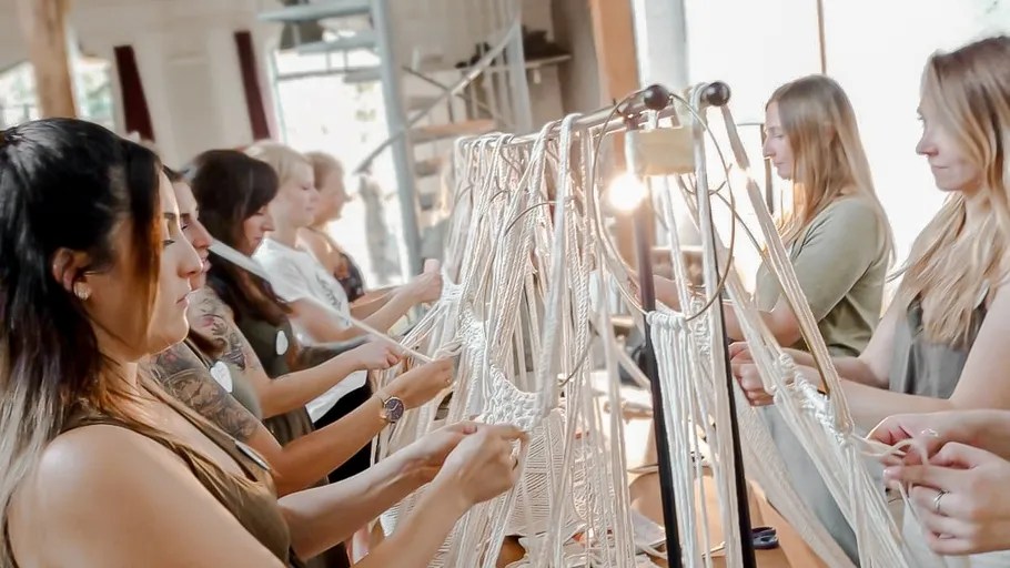 Women make artistic rope arrangements together in bright surroundings.