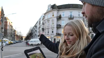 Two people looking at a map app on a tablet, outdoors.