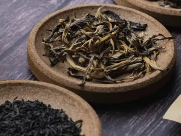 Three bowls of various tea leaves on a table.