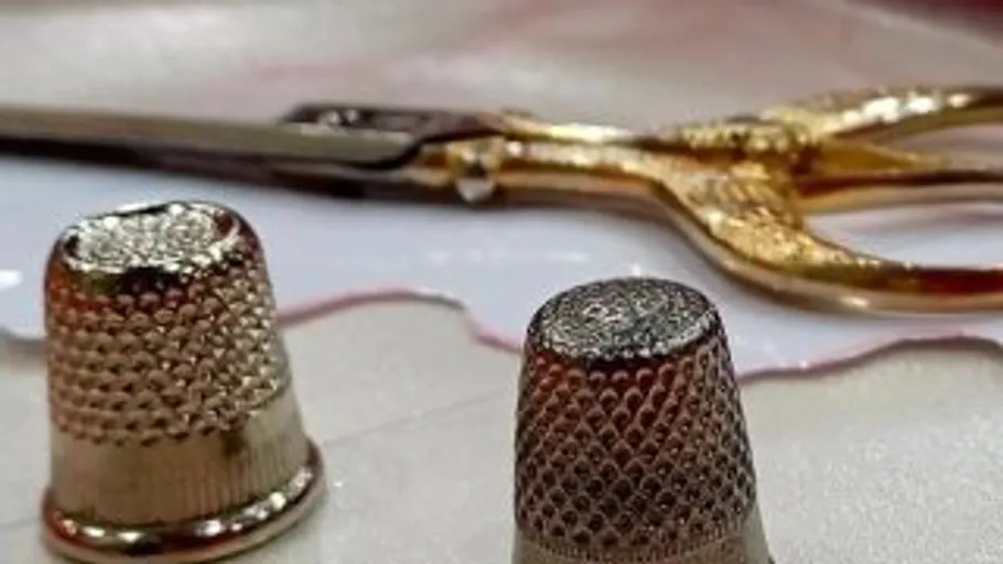Thimbles and scissors on sewing material.