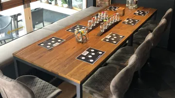 Wooden table with placemats and chairs, indoor setting.