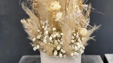 Dried flower arrangement in ceramic pot.