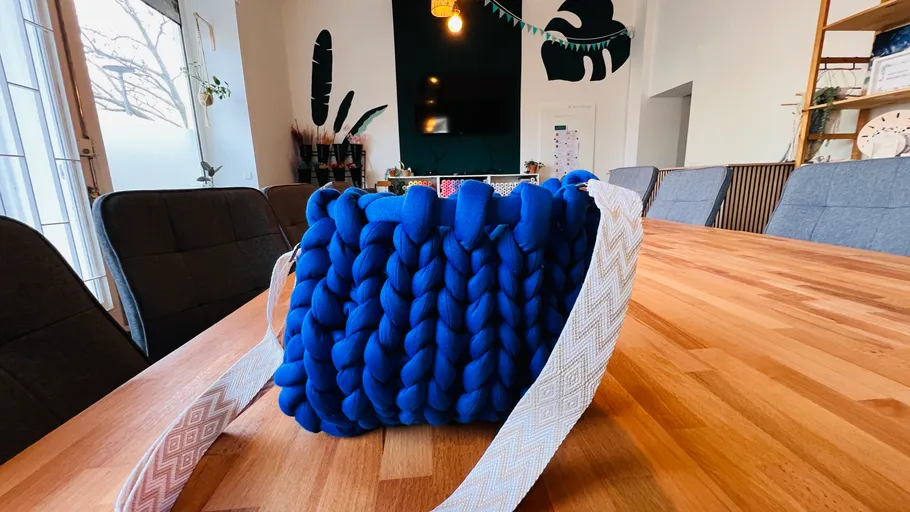 Blaue Stricktasche auf einem Holztisch.