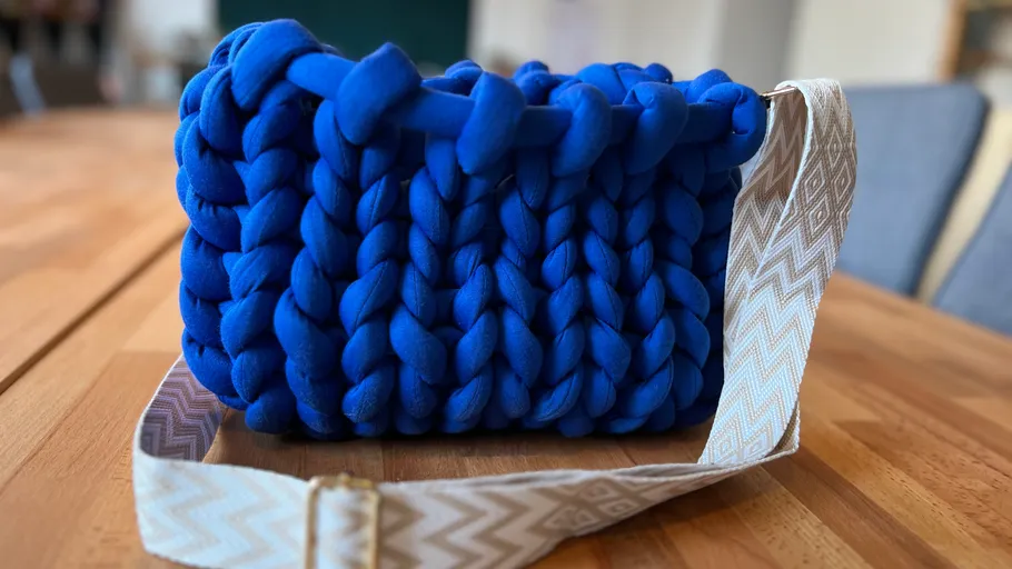 Blaue Stricktasche auf Holztisch.