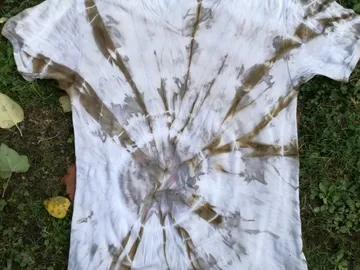 T-shirt with spiral color pattern lying on grass.