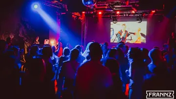 Leute tanzen in einem Club mit roten Lichtern.