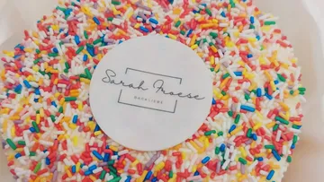 Cake covered in colorful sprinkles with printed label.