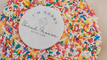 Cake with colorful sprinkles and apology message.