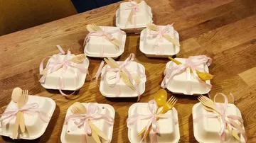 Decorated food containers with ribbons on table.