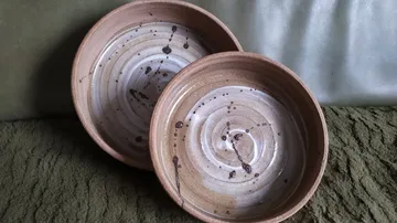 Two ceramic bowls with swirl design on fabric.