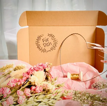 Pappschachtel mit getrockneten Blumen und Faden.