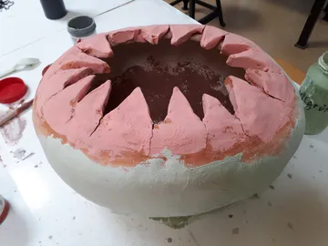 Tontopf mit Zähnen, unvollendet, auf einem Tisch.