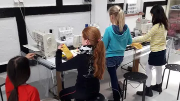 Children sewing with machines in a classroom.