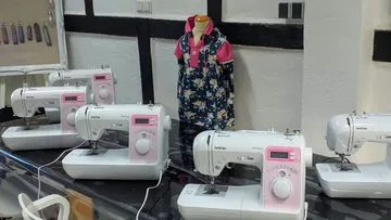 Sewing machines on table with dress mannequin.