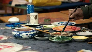 Person painting with brushes on colorful palette.