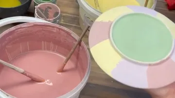 Hand-painted ceramic plate above paint bucket.