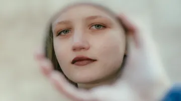 Das Gesicht spiegelt sich draußen im kleinen Handspiegel wider.