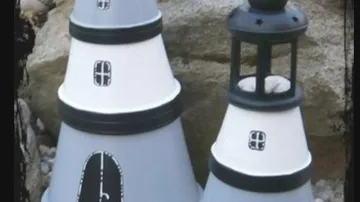 Bemalte Leuchttürme in Blumentöpfen auf Felsen.