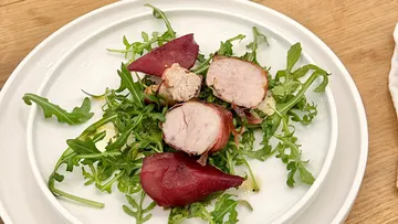 Sliced meat and greens on a white plate.
