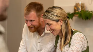 Two people smiling in a room with plants.