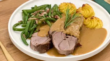 Lamb with green beans and potatoes on plate.