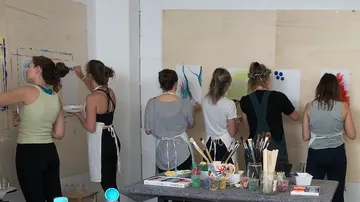 Sechs Frauen malen auf Holztafeln im Raum.