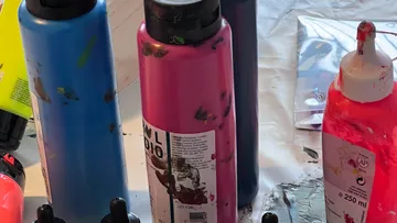 Bunte Farbdosen auf unordentlichem Kunsttisch.