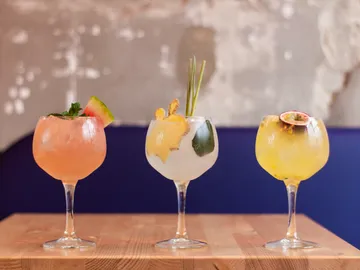 Drei Cocktails stehen auf einem Holztisch.
