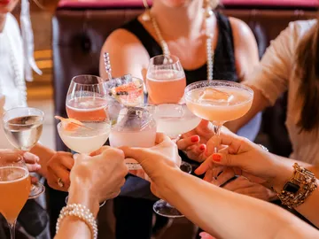Gläser mit Cocktails werden in einer Feierlaune angestoßen.