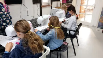 Kinder nähen mit Maschinen im Klassenzimmer.